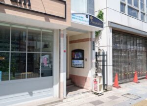 施設の玄関・車寄せ。白を基調とした入口で、看板と案内表示が確認できます。